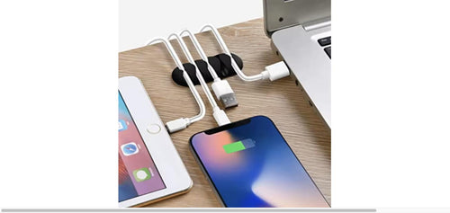 A black cable organizer holding several white charging cables plugged into a laptop and two smartphones on a wooden desk.